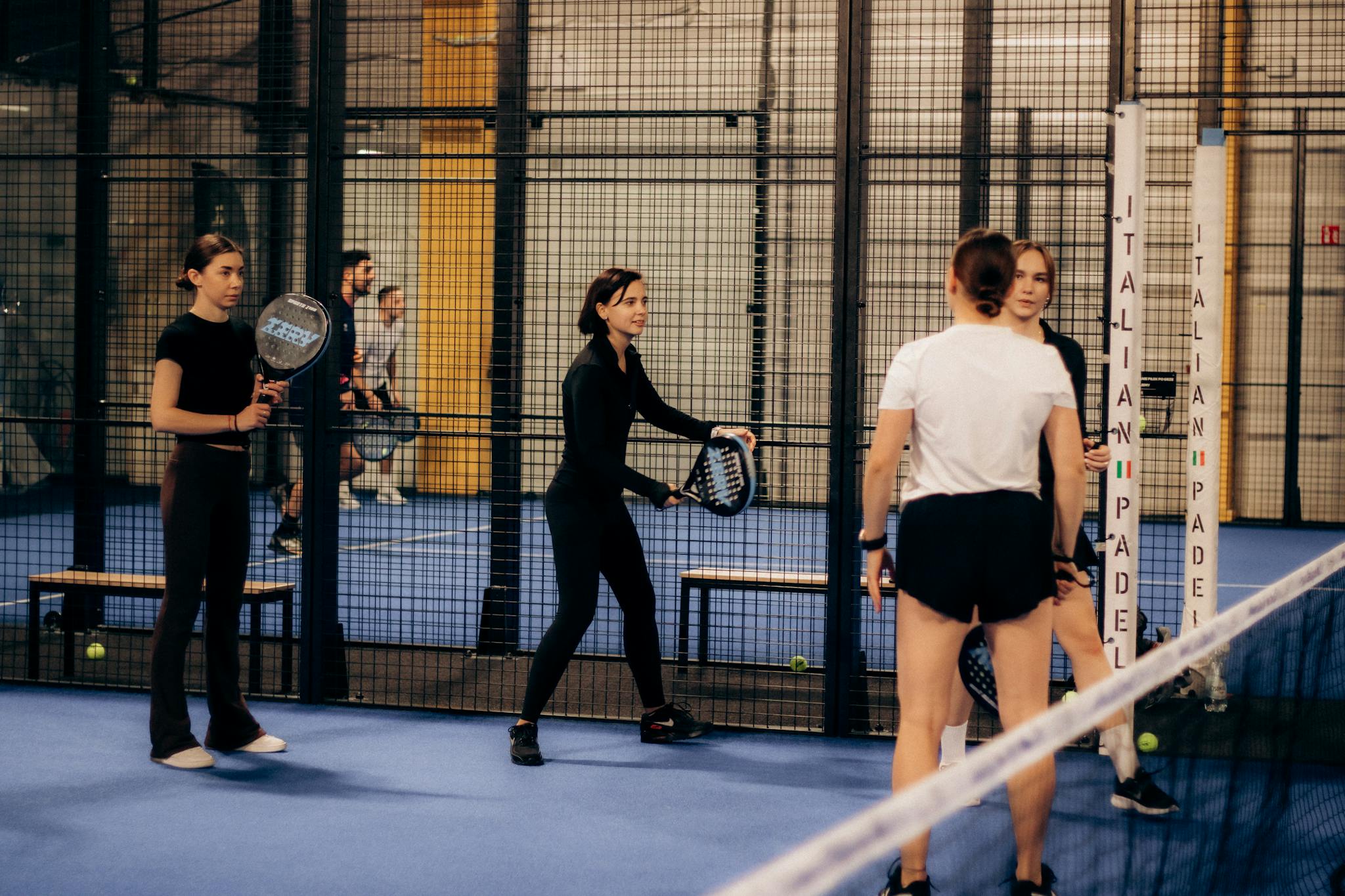 Indoor padel tennis game with multiple players preparing for a match.